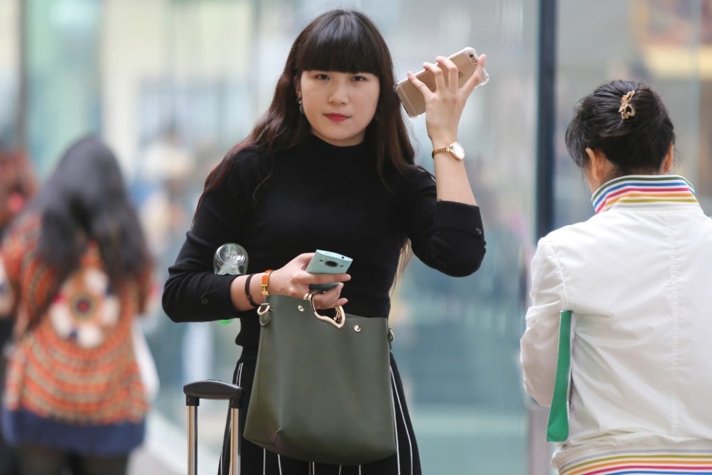 A woman in Causeway Bay listens to one mobile phone while holding another. Getting cold calls has been a problem in Hong Kong for many years, but seems to be getting worse these days. Photo: Xiaomei Chen