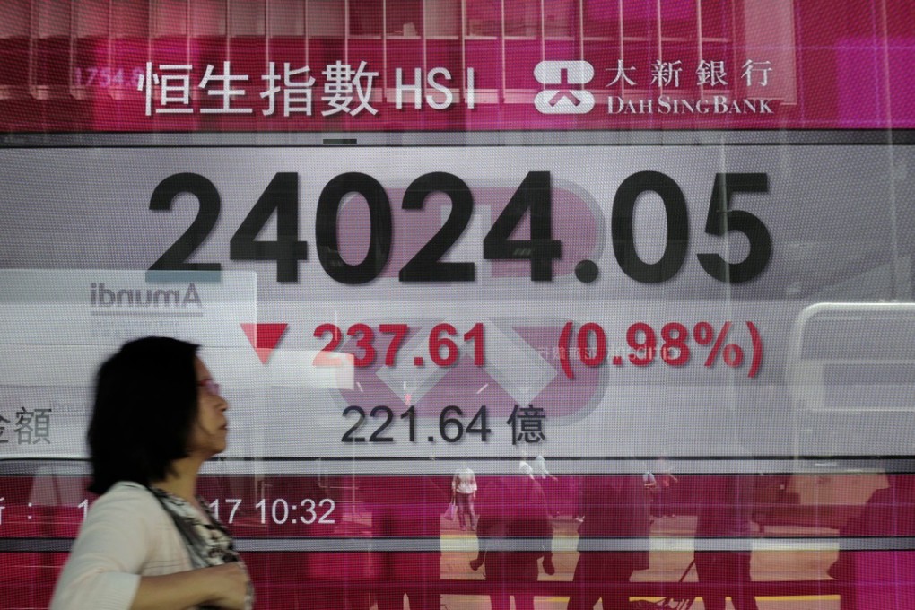 A woman walks past an electronic board showing the Hong Kong share index outside a local bank in Hong Kong, Tuesday, April 18, 2017. Asian stocks were seen ending the week lower with the US jobs data due out later on Friday. Photo: AP