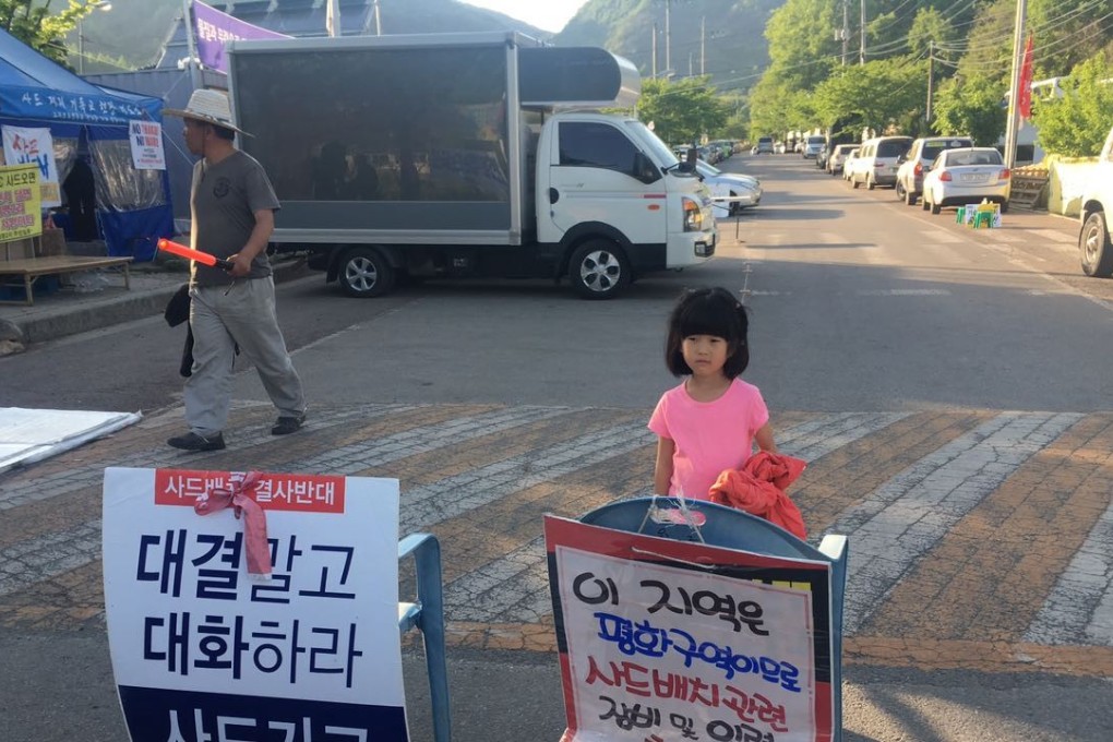 A child stands near a protest banner at Seongju in South Korea, the location for the deployment of Terminal High Altitude Area Defence (THAAD) anti-missile system. Photo: Liu Zhen