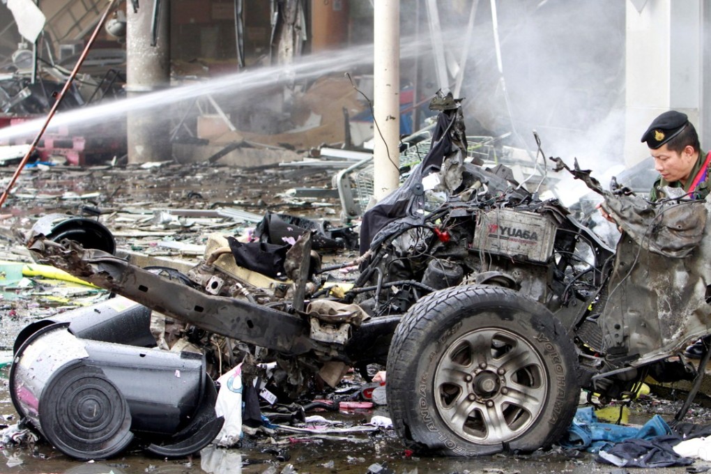 Remains of destroyed car are seen at a blast site outside a supermarket in Pattani. Photo: Reuters