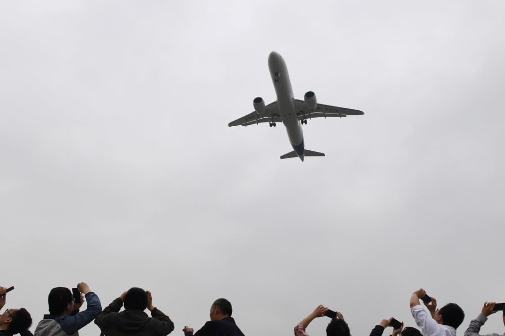 Spectators take photos as they watch the Comac C919, China's first large passenger jet, coming in for a landing on its maiden flight at Shanghai's Pudong airport. Photo: REUTERS/Greg Baker/Pool