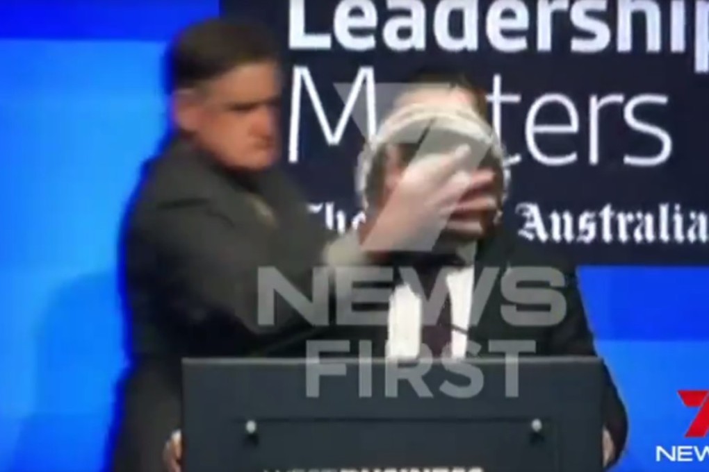 Alan Joyce, the head of Australia’s flag carrier, was speaking at the event in Perth, capital of Western Australia state, when a man in a business suit walked onto the stage, reached around to rub the pie in his face, and calmly walked away, Photo: 7 News