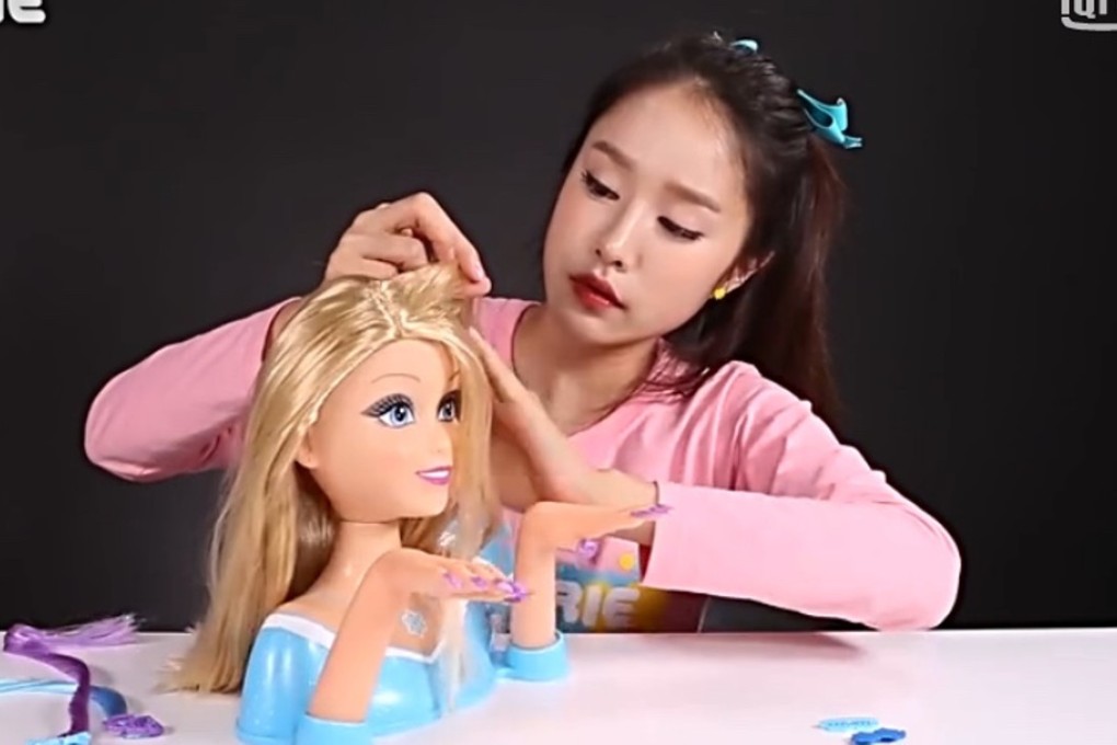 Chinese toy video host Carrie combs a doll’s hair.