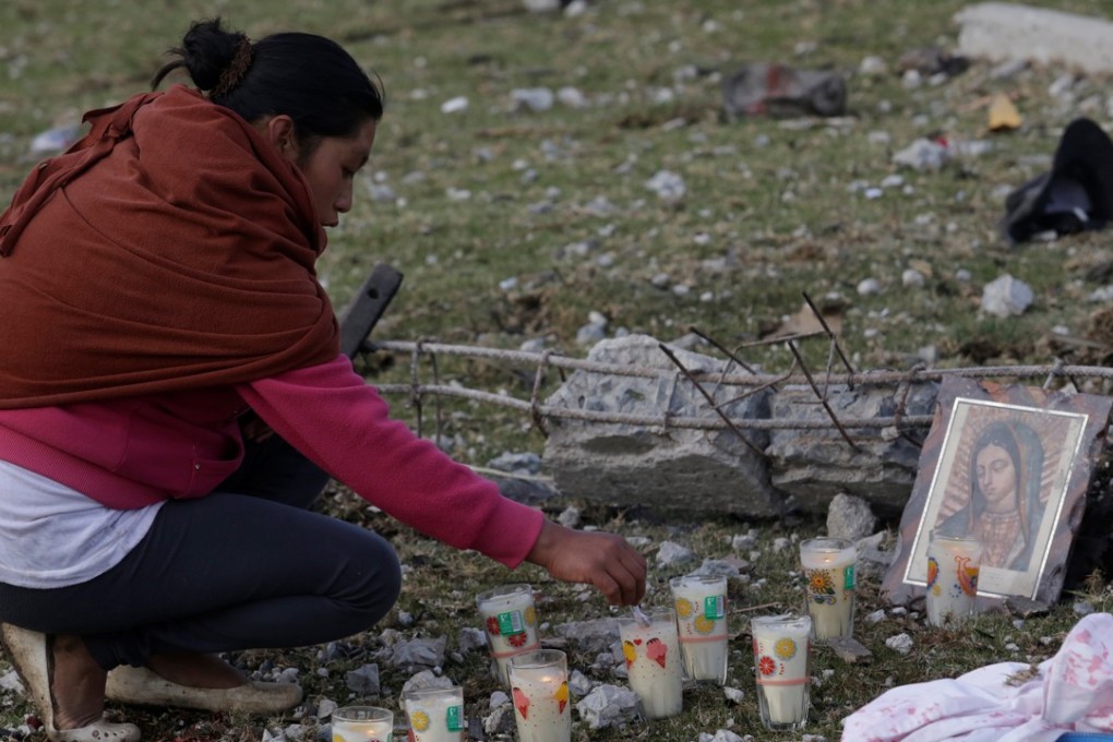 A resident arranges votive candles next a religious image of Our Lady of Guadalupe near debris after fireworks stored in a house exploded in San Isidro, Chilchotla, Mexico. Photo: Reuters