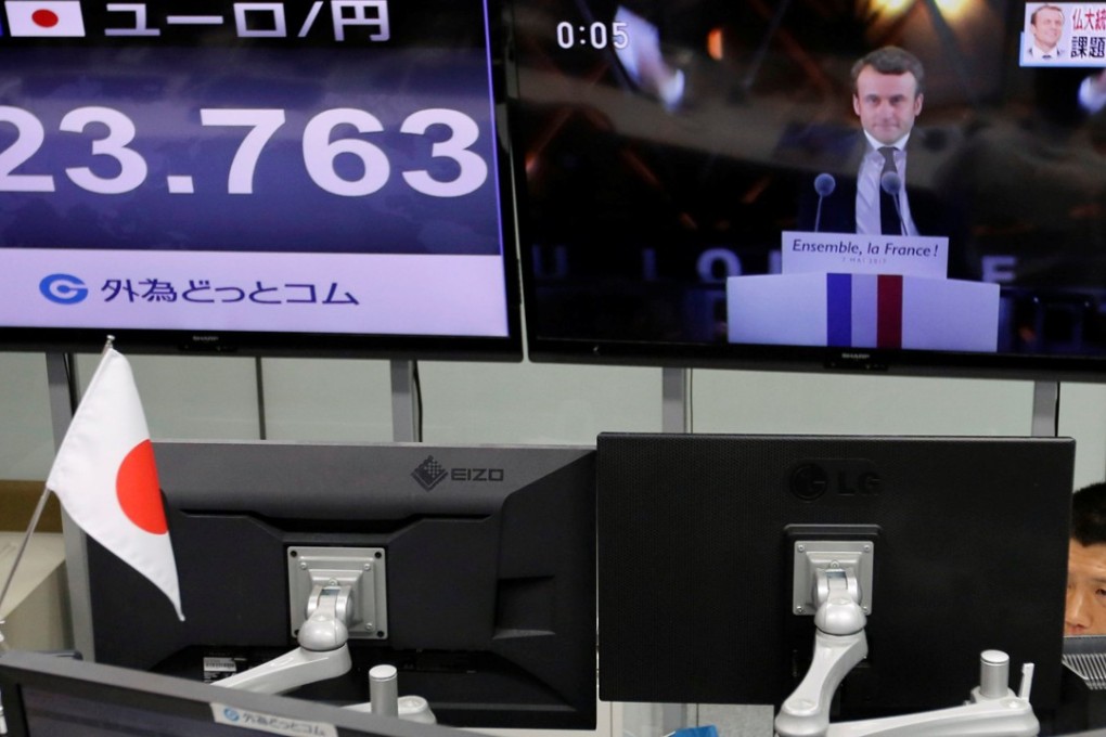 An employee of a foreign exchange trading company works near monitors showing French President-elect Emmanuel Macron (top R) on TV news and the Japanese yen's exchange rate against the euro in Tokyo, Japan. The dollar moved to an 8-week high against the Japanese yen. Photo: Reuters