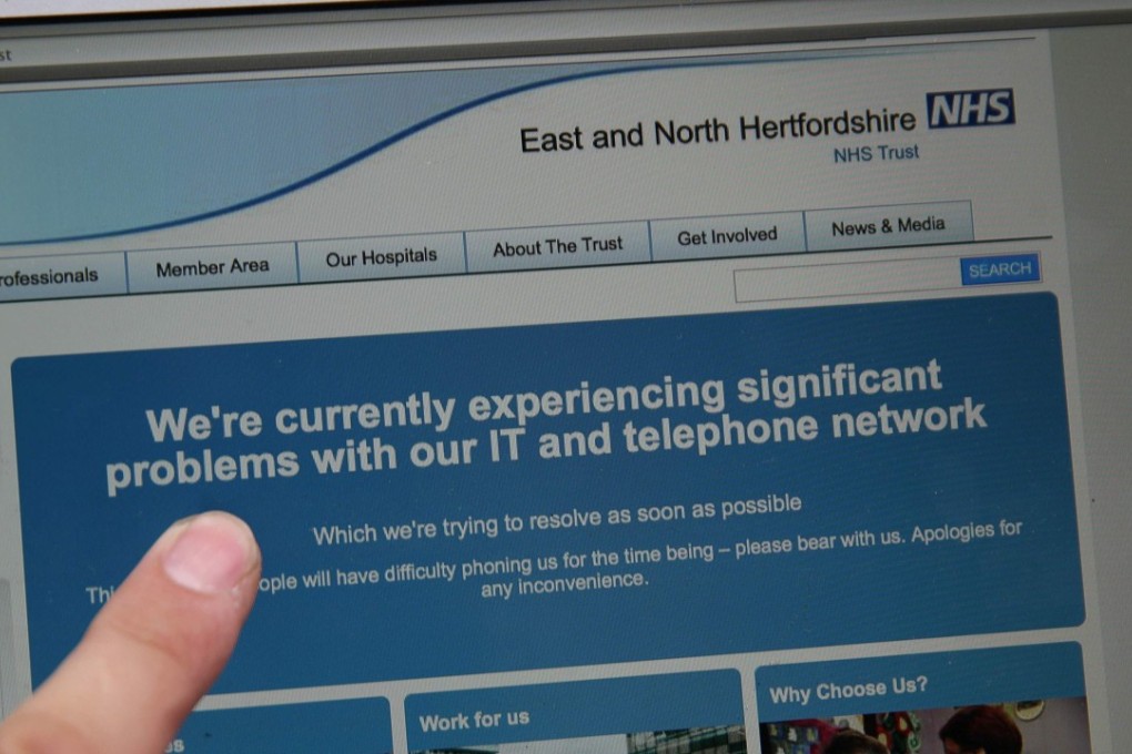 In this posed picture photograph, a woman points to the website of the NHS: East and North Hertfordshire notifying users of a problem in its network, in London on May 12, 2017. Several British hospitals were hit by cyber attacks on Friday, the country's health service said, forcing some to divert ambulances to other clinics and urge people not to try to contact their doctors. The attacks have now spread worldwide. Photo: AFP