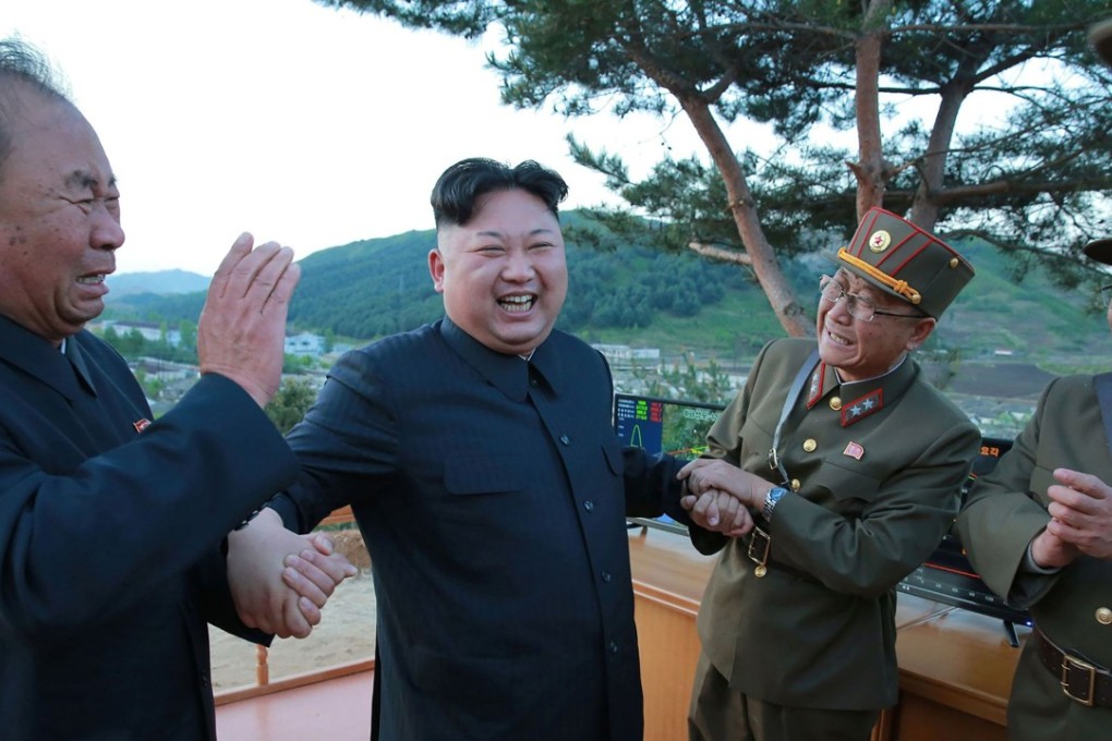 North Korean leader Kim Jong-un (second from left) shows his joy on Sunday over the successful test launch of a medium to long-range missile. Photo: AFP