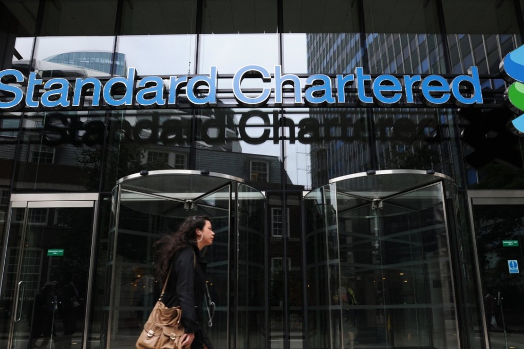 A person walks in front of a Standard Chartered bank in London. The lender is being asked by two of the world’s biggest asset managers to buy back a stake in a Singapore company it had sold off a year ago. Photo: EPA
