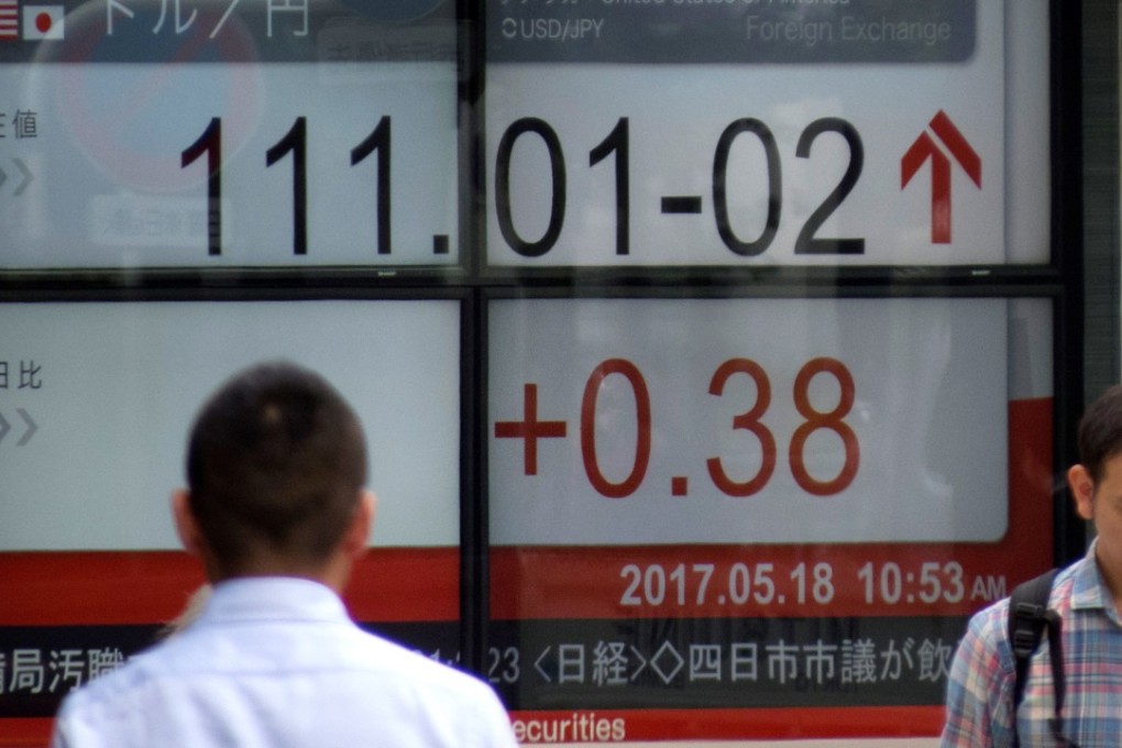 Pedestrians walk past a quotation board flashing the current foreign exchange rate gainst the US dollar in front of a securities company in Tokyo. The US dollar had its worst trading week due to the political issues houding US President Donald Trump. Photo: AFP