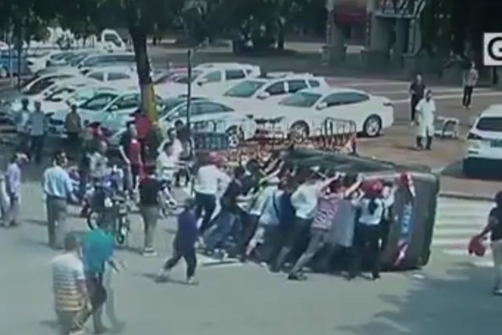 Passers by in Huizhou teamed up to lift the overturned 2-tonne minivan to pull out trapped delivery man. Photo: SCMP handout