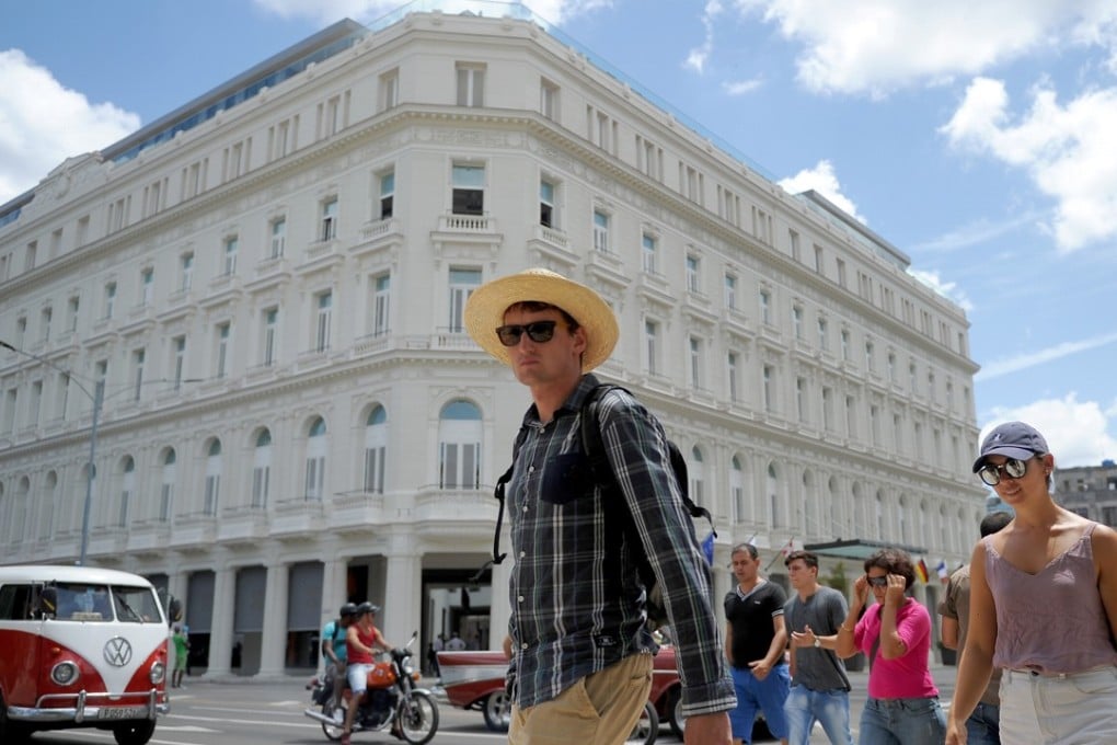 Tourists walk near the Manzana Kempinski Hotel, the first luxury five star plus tourist facility in Cuba. Photo: AFP