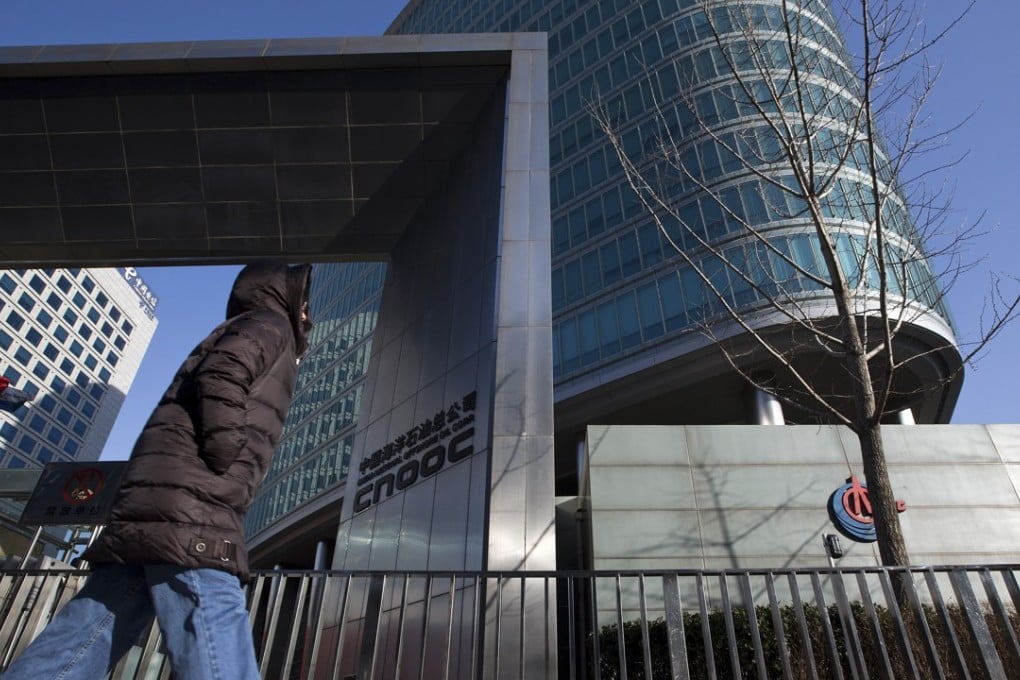 A woman walks past the headquarters of the state-owned China National Offshore Oil Corporation in Beijing. Photo: AP
