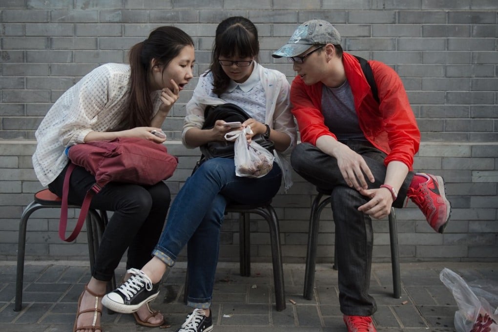 Young Chinese looking at a smart phone. With the technology the army can go to the frontline at anytime. Photo: AFP