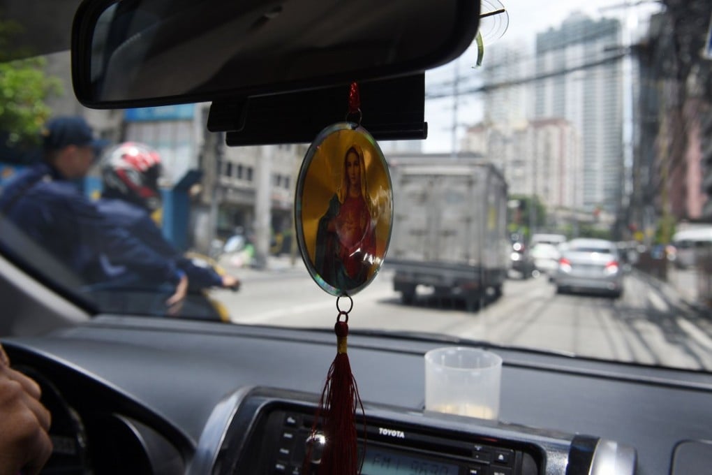 A Filipino taxi driver displays a religious icon inside his vehicle in Manila. Philippine authorities have banned hanging rosaries and religious icons off car dashboards because of safety concerns. Photo: AFP