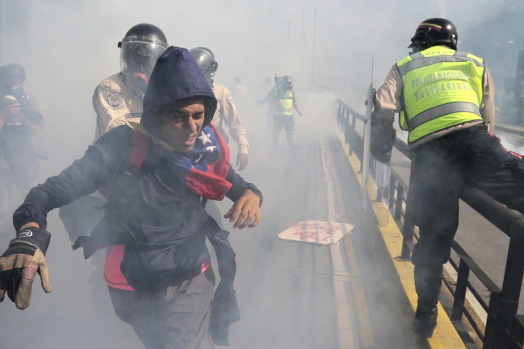 A protester flees government security forces during a demonstration by opponents of President Nicolas Maduro who gathered to block a major highway in Caracas, Venezuela, on May 20. Photo: AP