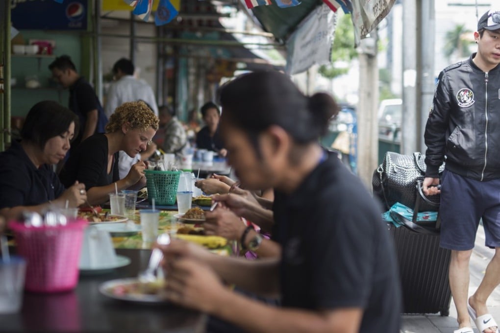 A tourist walks next to a street food stall in Bangkok, Thailand. Photo: EPA