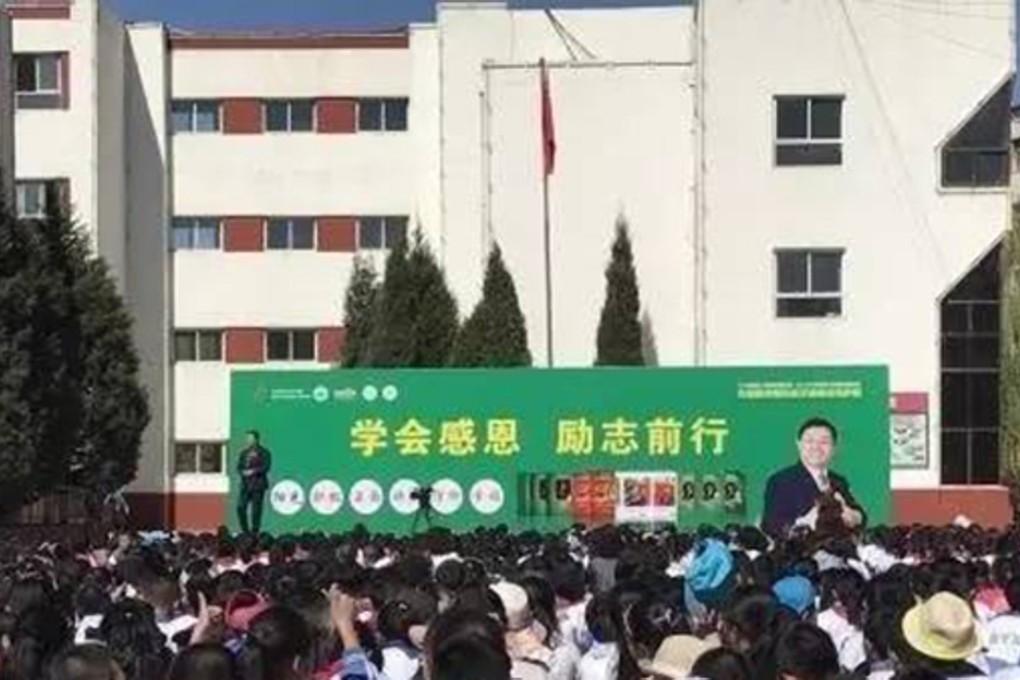Ouyang addresses the pupils from a stage bearing a large image of himself. Photo: Handout