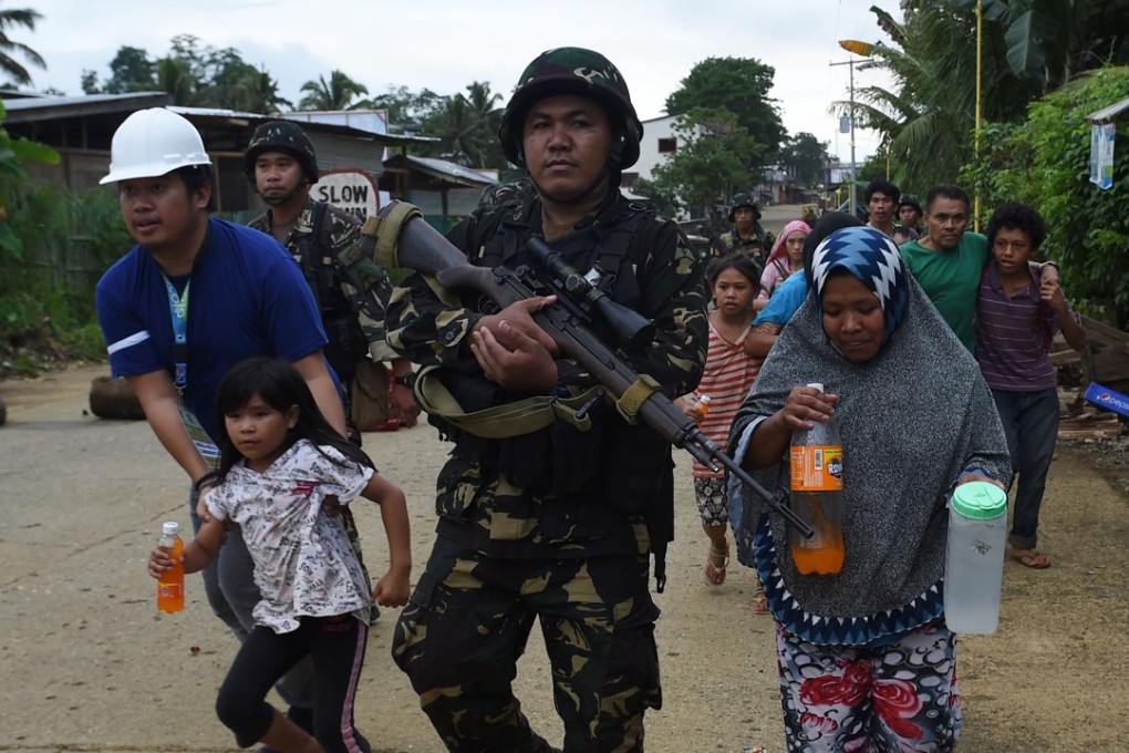 A rescuer (L) helps a child and others evacuate from their homes in a village on the outskirts of Marawi on the southern island of Mindanao on May 31, 2017, as fighting between government forces and Islamist militants continues. Philippine troops have killed 89 Islamist militants during more than a week of urban battles but a final showdown is expected to be fierce as the gunmen protect their leaders and hold hostages, authorities said on May 31. Photo: AFP