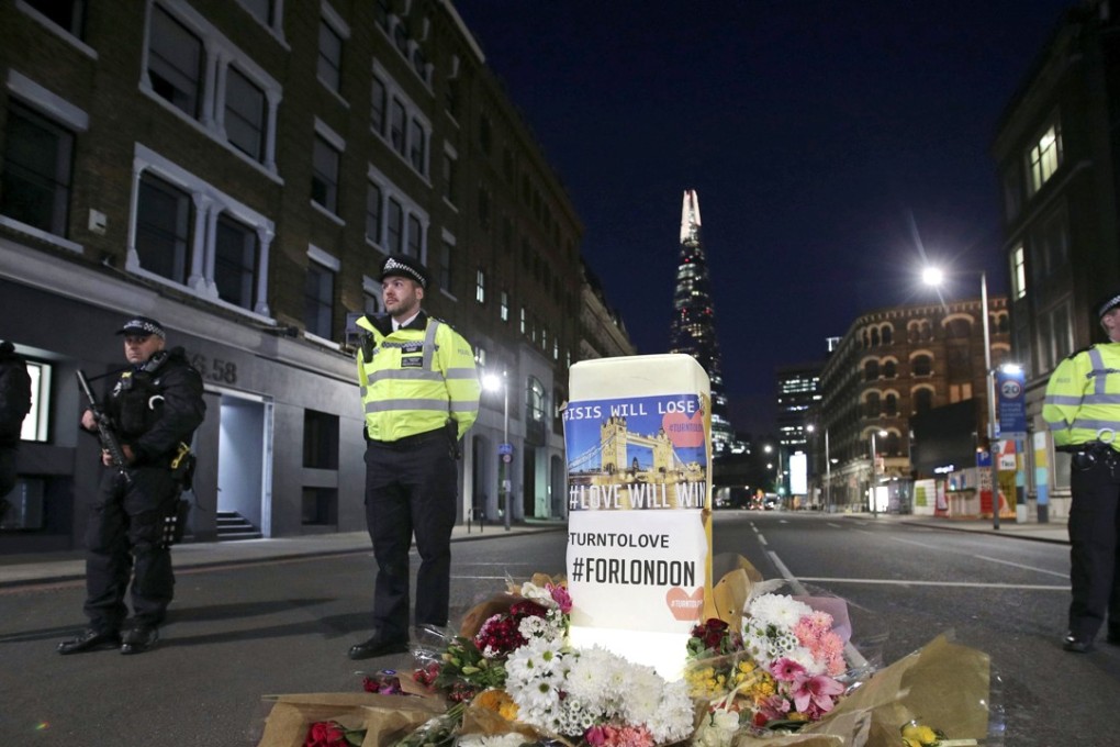Police officers on duty stand next to floral tributes on Southwark Street in London, on Sunday, near the scene of Saturday's terror attack. Photo: AP