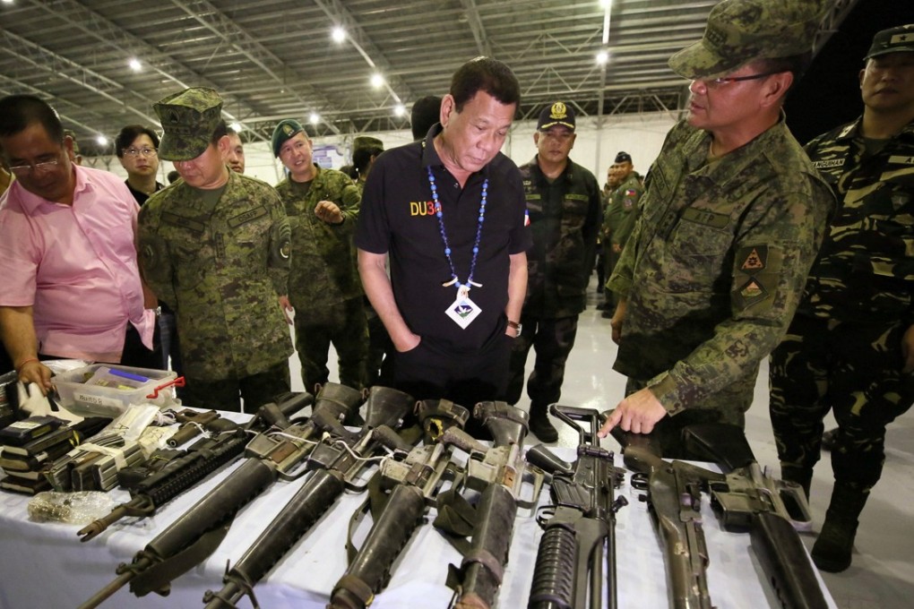 Philippine President Rodrigo Duterte looks at rifles on display during his visit to a military camp. Philippine opposition lawmakers on Monday asked the Supreme Court to reject Duterte’s imposition of martial law in the south of the country, branding it unconstitutional. Photo: EPA