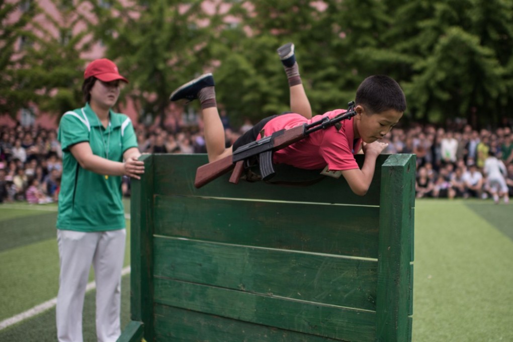 A boy carrying a mock rifle completes an obstacle course. Photo: AFP
