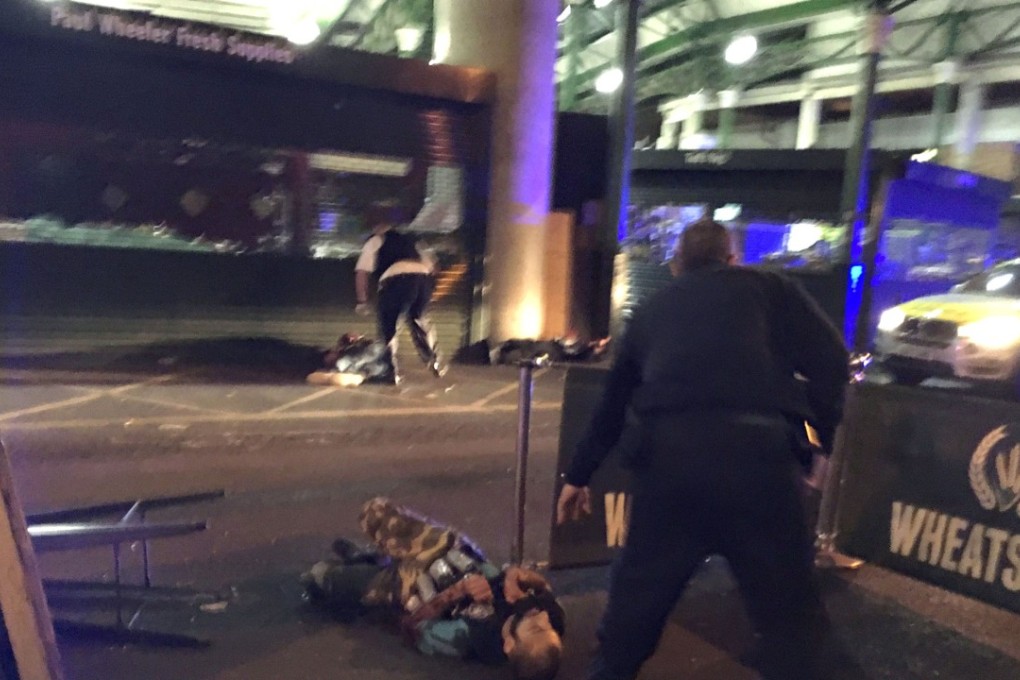 Armed police stand over a suspect shot at the scene of a terror attack outside Borough Market in central London. Photo: AFP
