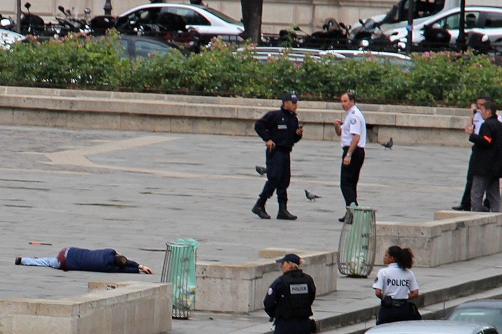 Police officers stand near a wounded attacker after shooting him outside Notre Dame cathedral in Paris on Tuesday. Photo: Reuters