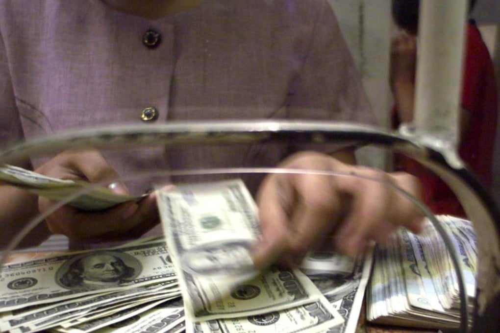 A Filipino woman counts US dollar notes inside a money changer’s in Manila. Photo: Reuters