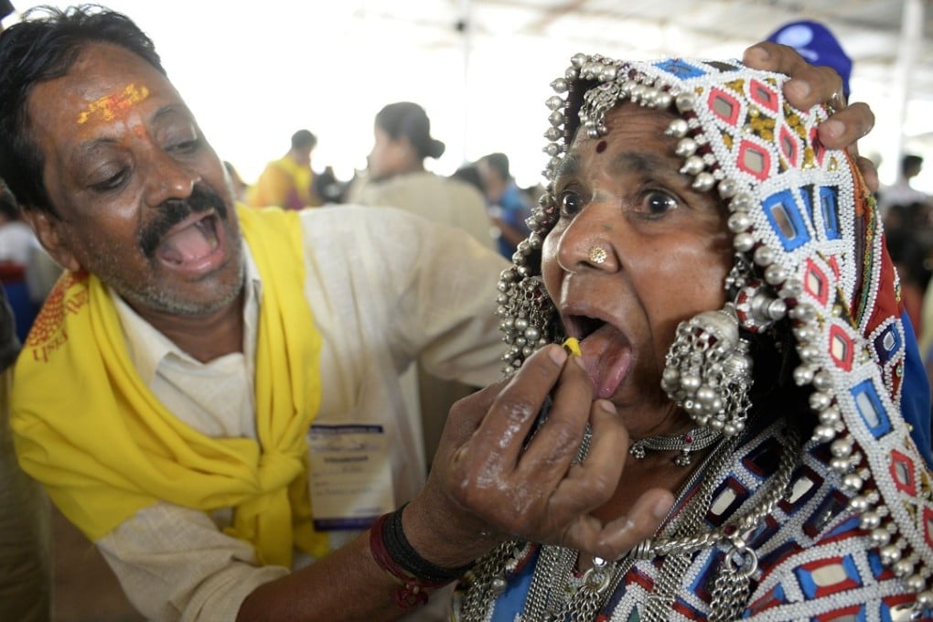 An Indian member of the Bathini Goud family administers the “fish medicine” to a Lambadi tribal woman. Photo: AFP