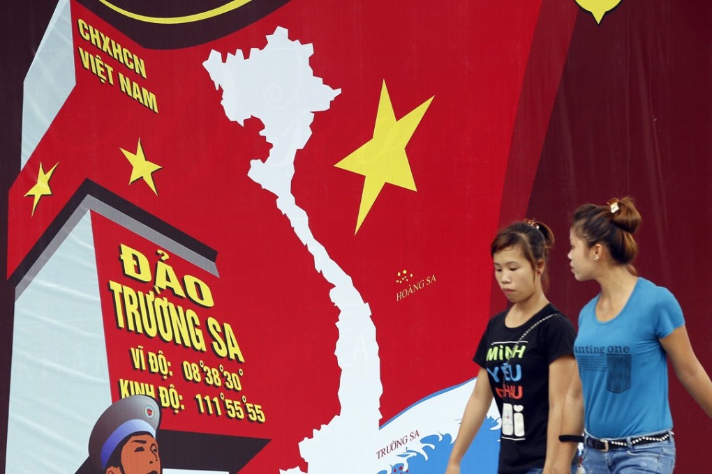 A file picture of two women passing a board featuring a map of Vietnam in Hanoi. Photo: EPA