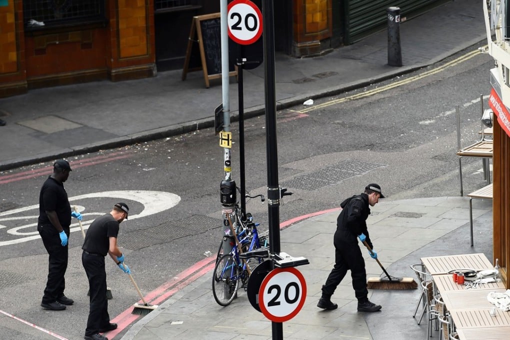 Police officers sweep the street outside a restaurant in Borough Market. Photo: Reuters
