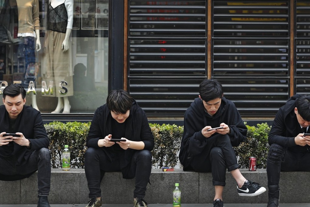 People browse their smartphones in Beijing. Jefferies predicts the mainland will have 588 million 5G subscribers by 2022. Photo: AP