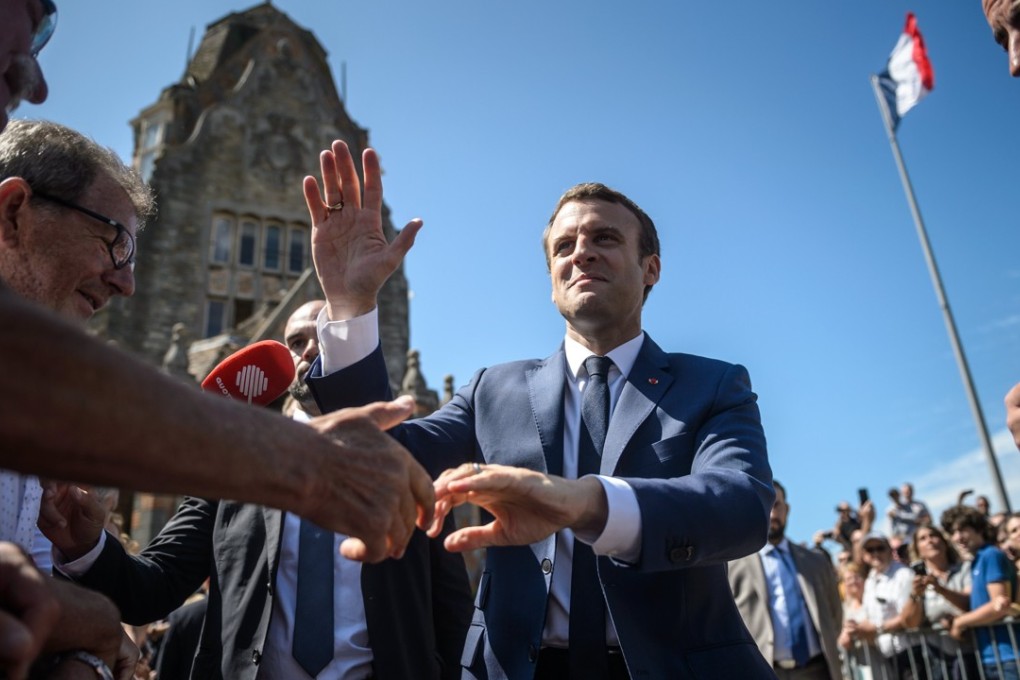 French President Emmanuel Macron shakes hands with members of the public as he leaves the polling station after voting in the first round of the French legislatives elections in Le Touquet, northern France. Photo: EPA