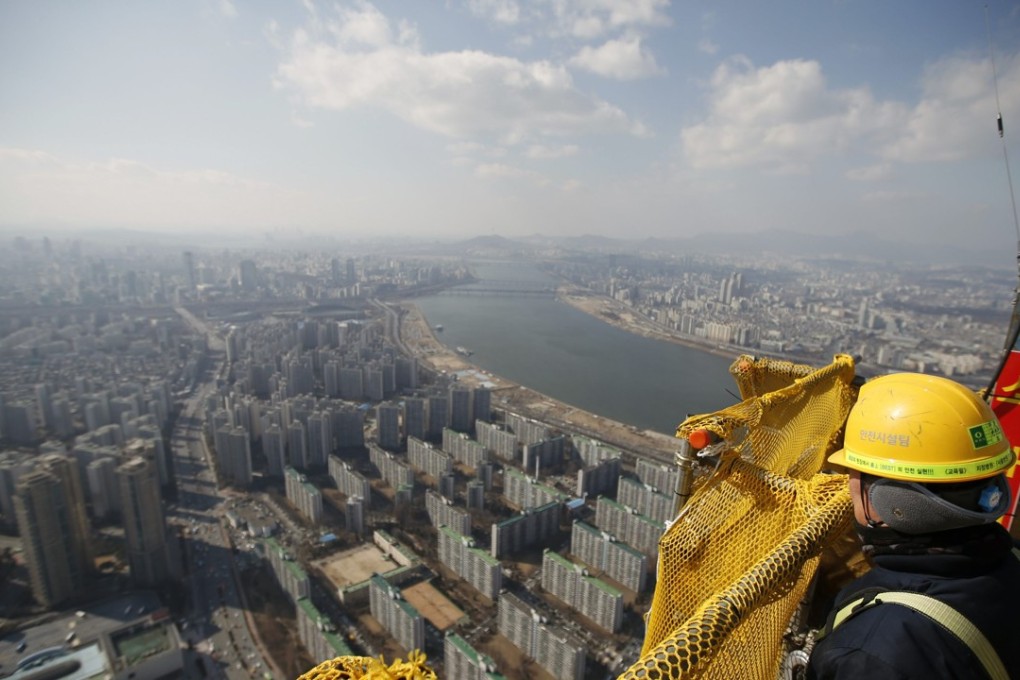 A construction worker looks out at the Seoul skyline. Photo: REUTERS/Kim Hong-Ji