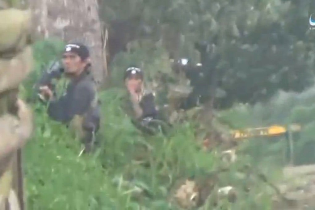 A still image taken from a video posted to a social media website by the Islamic State-affiliated Amaq News Agency on June 12, 2017, shows militants carrying weapons behind bushes in Marawi City. Photo: Reuters