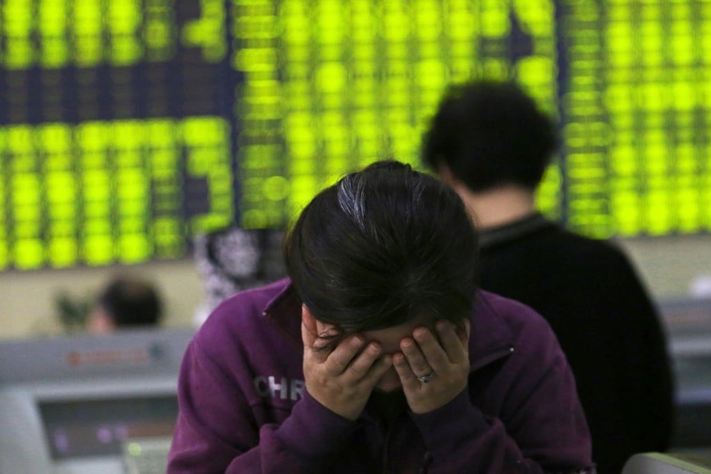 A woman rubs her face as she stands at a computer terminal in a stock brokerage house in Nantong in eastern China's Jiangsu province. Contrary to global conventions, mainland China’s capital market uses green to denote declines, and red to denote advances. Photo: EPA