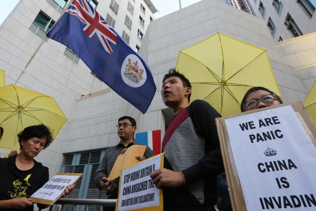 Pro-democracy demonstrators hold the colonial flag and symbolic yellow umbrellas as they stage a protest outside the British consulate in Admiralty, on November 21, 2014, during the Occupy movement in Hong Kong. Photo: Felix Wong
