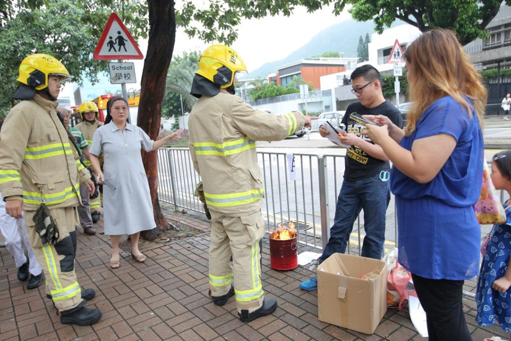 Protesting parents and firemen stand outside Holy Family Canossian School in Kowloon Tong. Photo: Handout