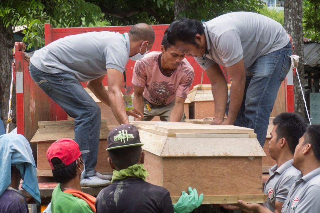 Funeral workers lift a coffin containing one a civilian. Photo: Reuters