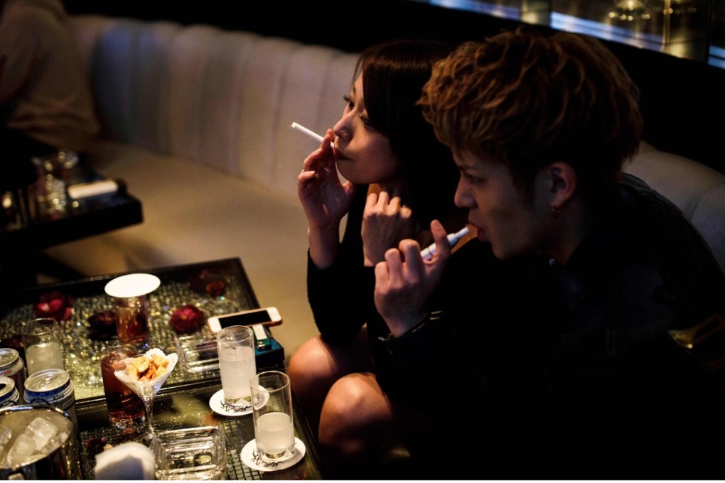 One patron smokes a traditional cigarette while the other uses an electronic version inside a club in the Kabukicho district of Tokyo. The World Health Organisation wants to make Tokyo a ‘smoke-free’ city in time for the Olympics in 2020. Photo: AFP