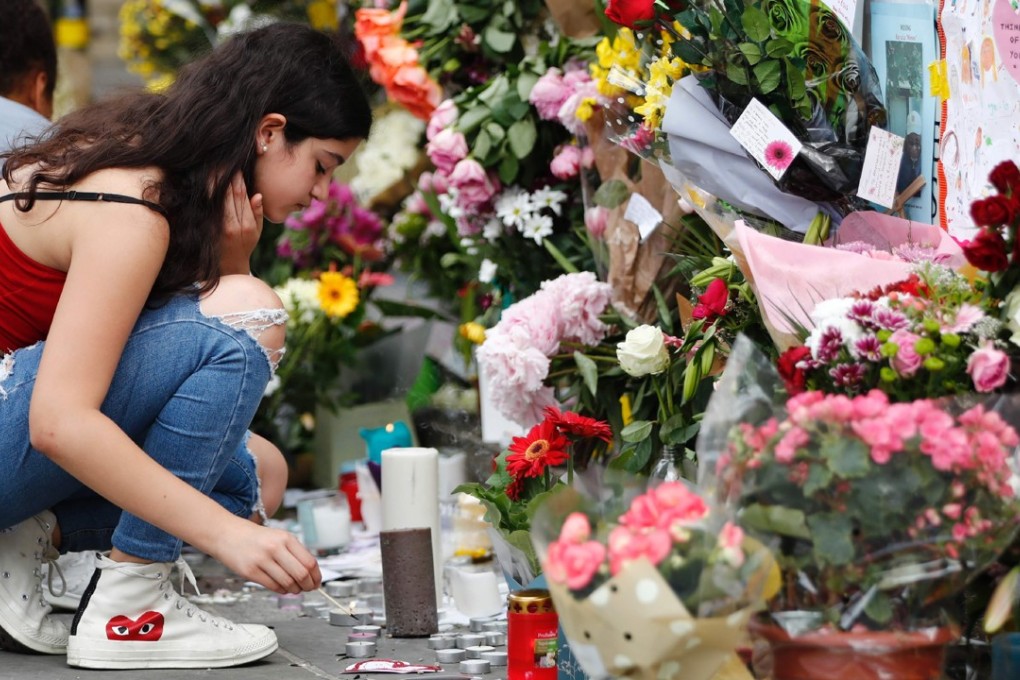 A girl lights a candle at a wall of tributes outside Notting Hill Methodist Church. Photo: AFP