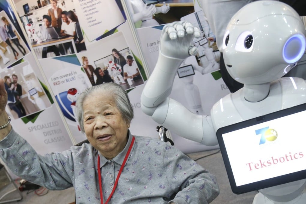 Fong Ying, 85, follows the dance steps of an intelligent robot, part of an exhibition at the Gerontech and Innovation Expo cum Summit at the Hong Kong Convention and Exhibition Centre in Wan Chai. Photo: David Wong