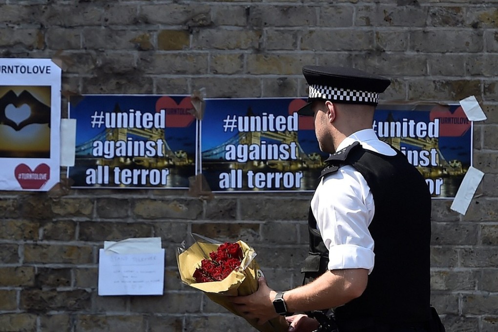 A police officer carries flowers to leave alongside of messages near to where a van was driven at Muslims in Finsbury Park, North London. Photo: Reuters
