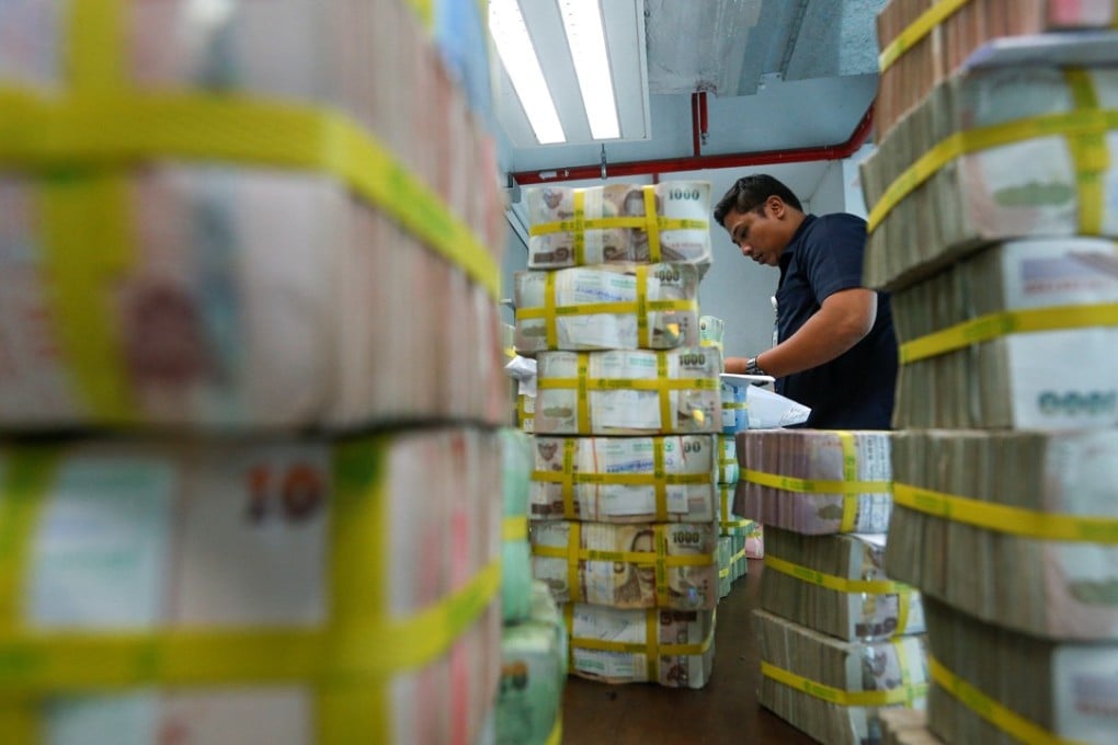 A bank worker gathers Thai baht notes in Bangkok. The devaluation of the baht on July 2, 1997, marked the start of the Asian financial crisis. Photo: Reuters