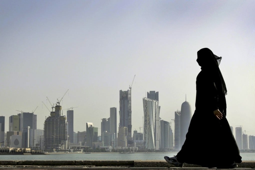 A Qatari woman walks in front of the city skyline in Doha. Photo: AP