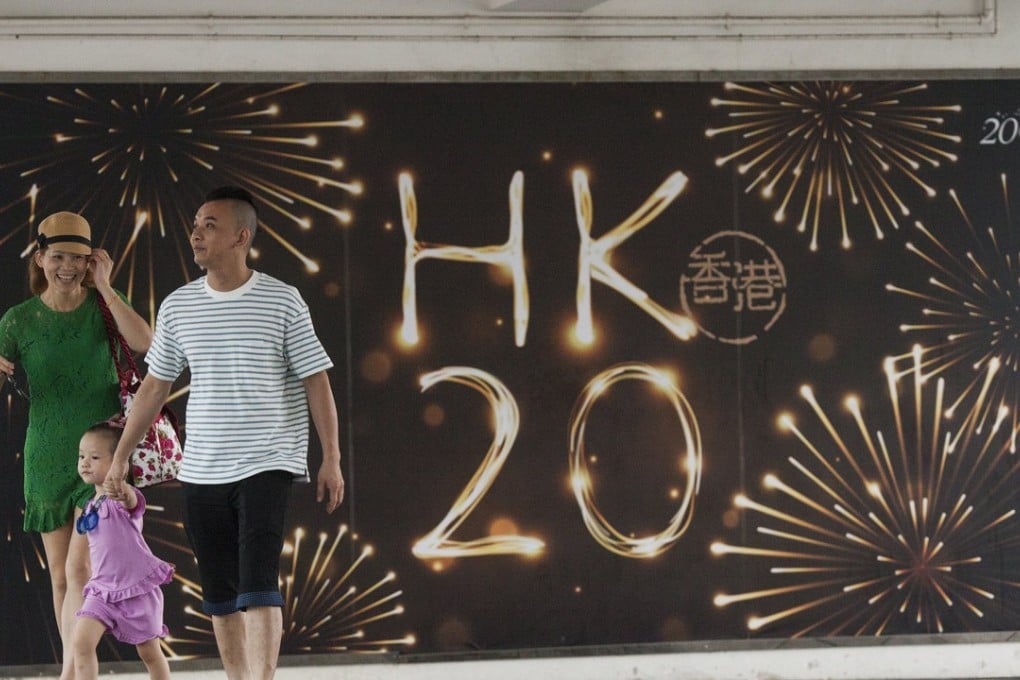 epa06040529 A young family walk past Hong Kong government signage promoting the 20th anniversary of the Hong Kong handover of sovereignty from Britain to China on 01 July 1997, near the Central ferry piers in Hong Kong, China, 21 June 2017. On upcoming 01 July 2017, Hong Kong will celebrate the 20th anniversary of its handover from Britain to China. Photo: EPA