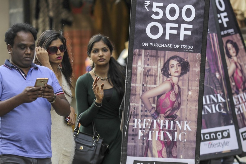 Pedestrians holding walks past people carrying advertisements for a local clothing store in Bangalore. India will soon have a national sales tax to replace the jumble of state levies that inhibit commerce. The goods-and-services tax (GST) will go a long way towards fulfilling Prime Minister Narendra Modi's pledge to make it easier to do business in the world's seventh-largest economy. Photo: Bloomberg