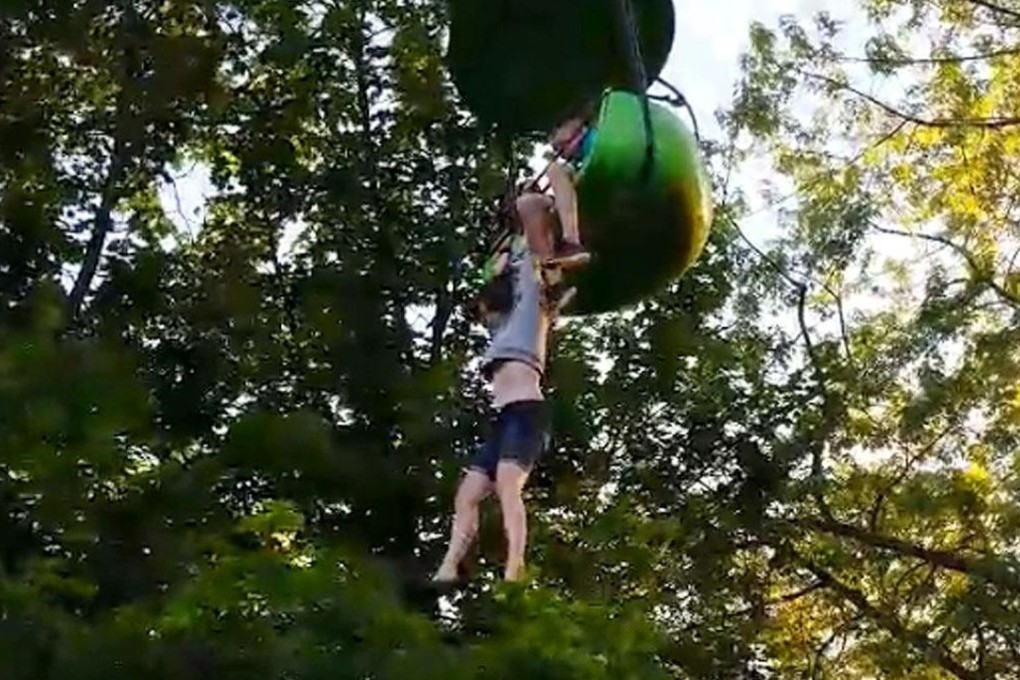 A 14-year-old girl dangles from an amusement park ride in New York state on Saturday before falling eight metres into the arms of people below. Photo: Loren Lent