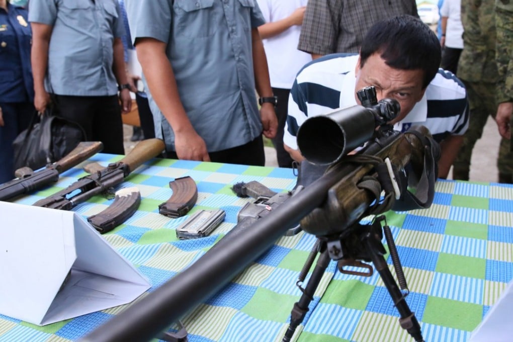 President Rodrigo Duterte looks through the scope of a sniper rifle in Butuan city, southern Philippines on June 17. File photo: EPA