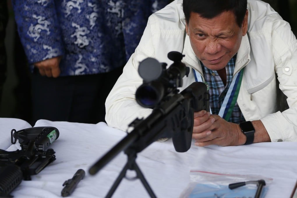 Philippine President Rodrigo Duterte checks the scope of a Chinese-made CS/LR4A sniper rifle during the ceremonial presentation weapons by China to the Philippines Wednesday. Photo: AP